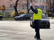 policjant w mundurze i żółtej kamizelce kieruje ruchem na skrzyżowaniu