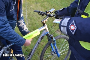policjant przekazuje elementy odblaskowe rowerzyście