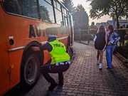 policjant sprawdza stan ogumienia autobusu