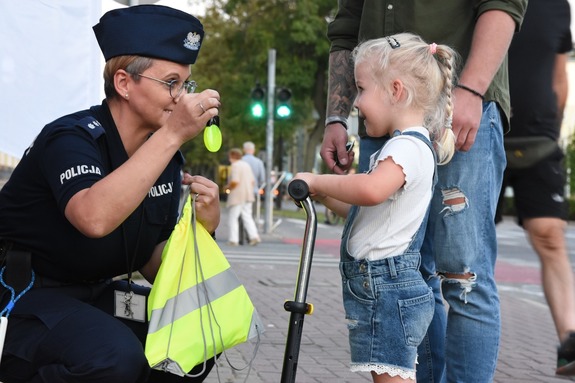 policjantka wręcza małej dziewczynce elementy odblaskowe
