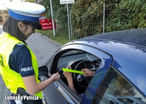 policjantka wręcza element odblaskowy kierowcy samochodu