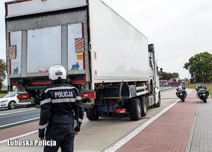 samochód ciężarowy - TIR obok policyjne motocykle i policjant w kasku motocyklowym