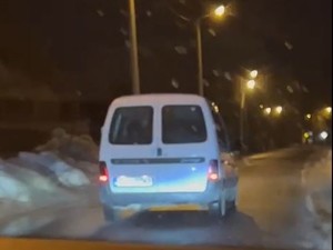 tył białego samochodu typu furgon na oświetlonej drodze o zmroku