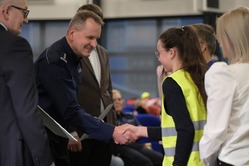 policjant wręcza dyplom uczennicy, zdjęcie zrobione na sali, w tle widać publiczność