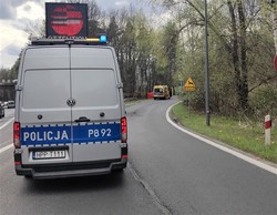 policyjny radiowóz typu bus oznakowany stoi na środku drogi w oddali widać miejsce wypadku