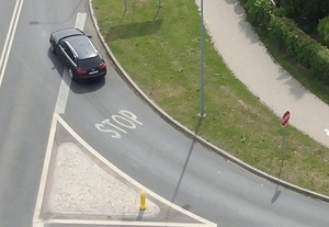 widok drogi z góry, samochód w kolorze szarym przed napisem STOP na jezdni