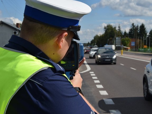 policjant obserwuje jadące samochody, trzyma wideorejestrator