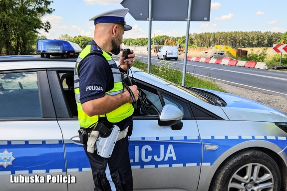 policjant stoi przy radiowozie